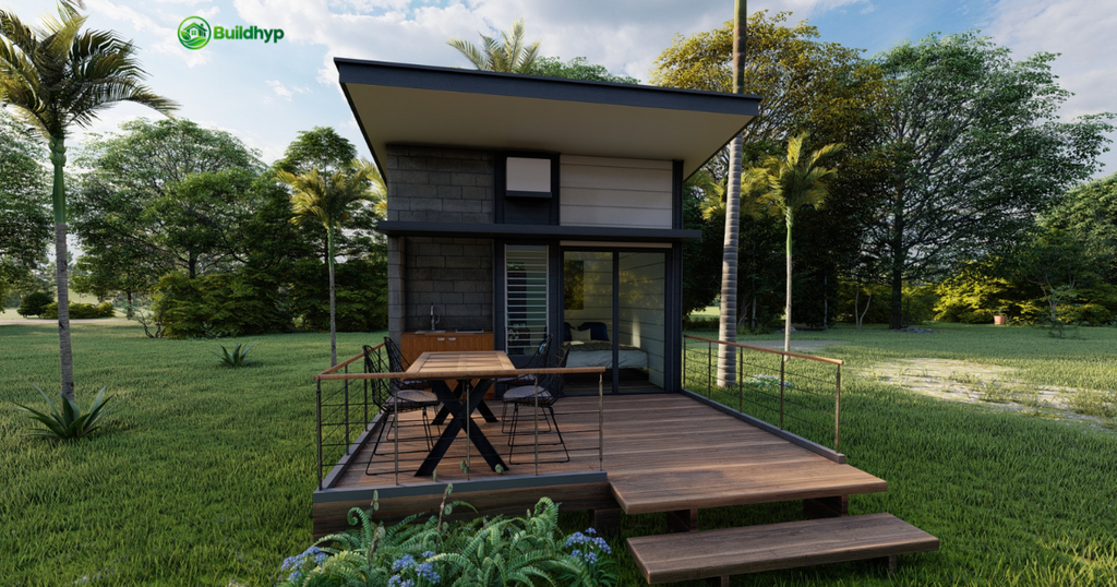 This modern tiny home, featuring grey stone and wood cladding, a large wooden deck, and a glass sliding door, is set in a green field, addressing the question: Can You Legally Live in a Tiny Home? 
