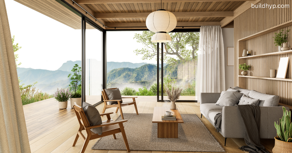 A contemporary mountain lodge living room featuring floor-to-ceiling glass sliding doors that open to scenic mountain views, furnished with neutral sofas and wooden accents.