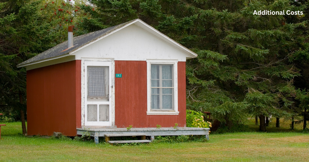 Charming red wooden retreat with white trim nestled against dense pine trees, showcasing simple Tiny Cabin Homes designed for cozy, affordable, off-grid living in nature.