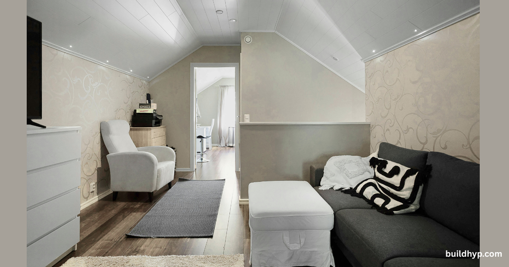 Cozy loft living room inside a Tiny Home On Wheels San Diego County, featuring a dark sofa, white armchair, patterned pillow, and clever built-in storage under the eaves. Perfect compact design. buildhyp.com